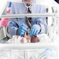 A premature infant is examined in the Newborn Intensive Care Unit.